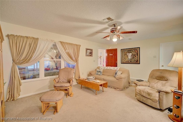 carpeted living room featuring ceiling fan and a textured ceiling