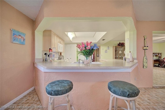 kitchen with a breakfast bar area, kitchen peninsula, and sink