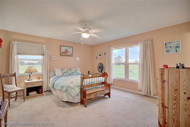 bedroom with a textured ceiling, light colored carpet, and ceiling fan