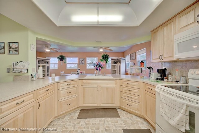 kitchen with sink, backsplash, kitchen peninsula, white appliances, and light brown cabinetry