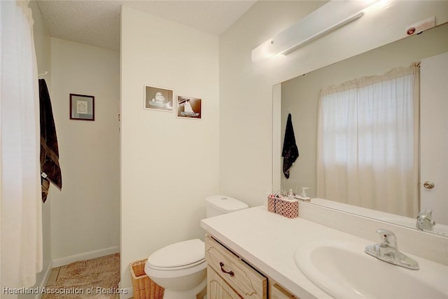 bathroom with a textured ceiling, vanity, and toilet