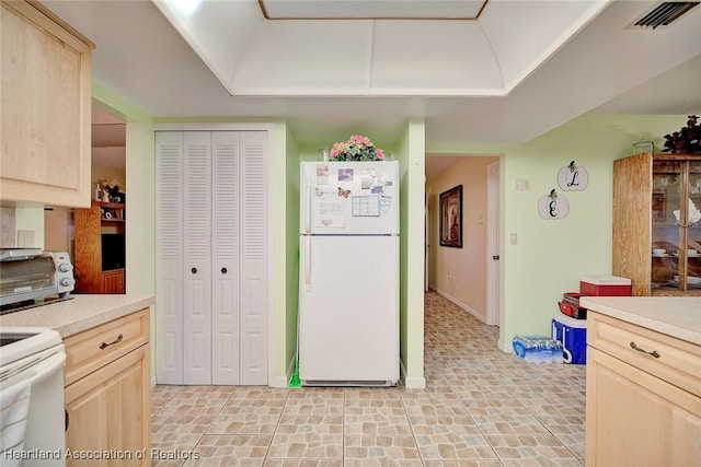 kitchen with light brown cabinetry and white appliances