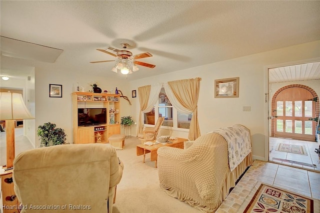 tiled living room with ceiling fan and a textured ceiling