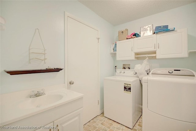 laundry area featuring cabinets, a textured ceiling, sink, and washing machine and clothes dryer