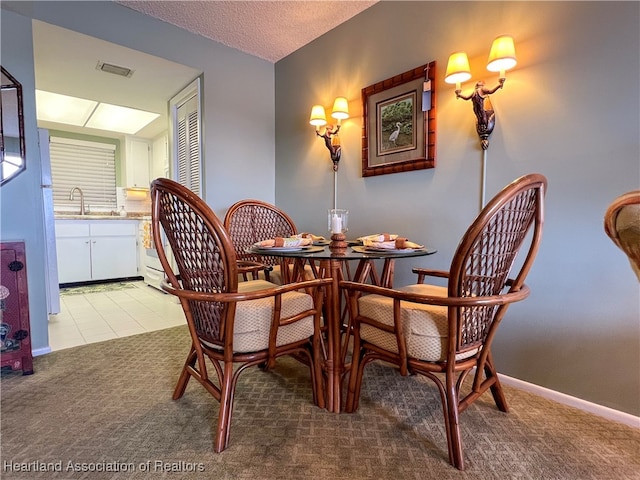 dining space featuring light carpet, a textured ceiling, and sink