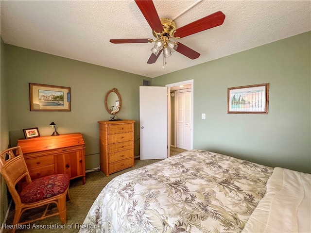 carpeted bedroom featuring ceiling fan and a textured ceiling