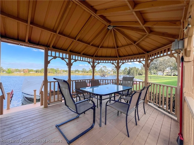 wooden deck featuring a gazebo, a boat dock, a water view, and a lawn