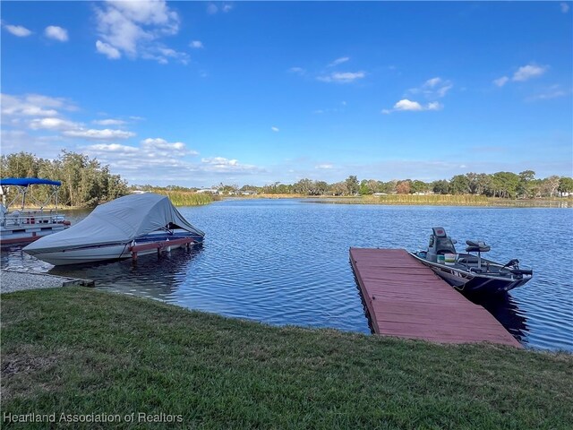 view of dock with a lawn and a water view