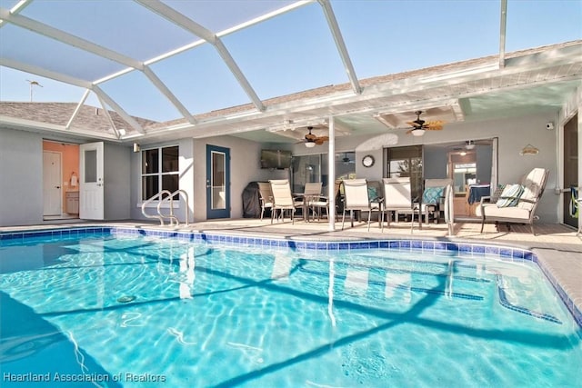 view of pool featuring glass enclosure, ceiling fan, and a patio area