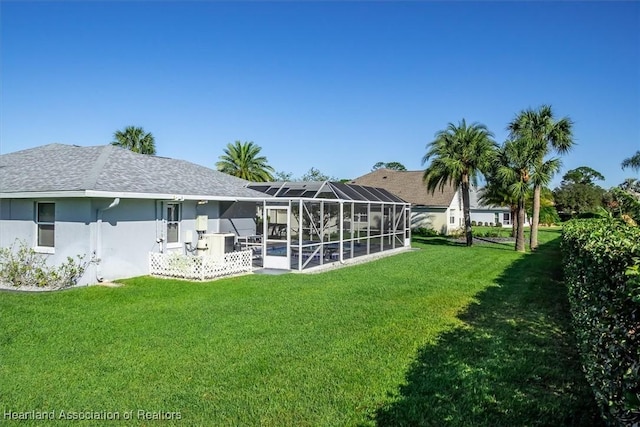 rear view of property with a swimming pool, a lanai, and a lawn