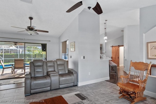 living room with a barn door and high vaulted ceiling