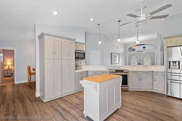 kitchen featuring appliances with stainless steel finishes, gray cabinets, vaulted ceiling, and a kitchen island