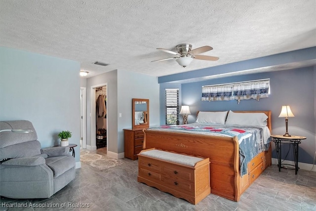 bedroom with ceiling fan, a walk in closet, a textured ceiling, and a closet