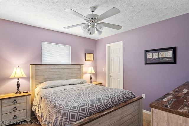 carpeted bedroom featuring ceiling fan and a textured ceiling