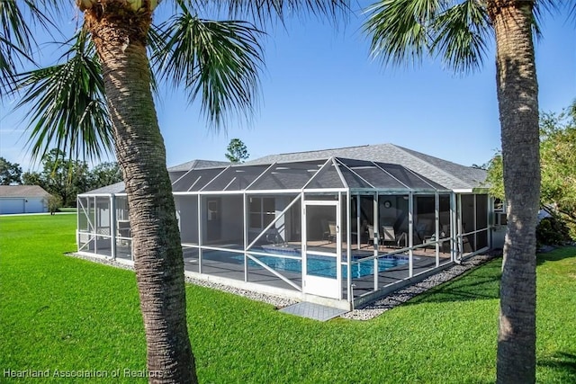 rear view of property featuring a lawn and glass enclosure