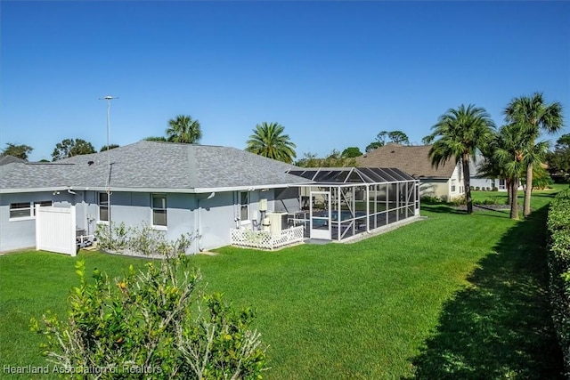 rear view of house featuring a lanai and a yard