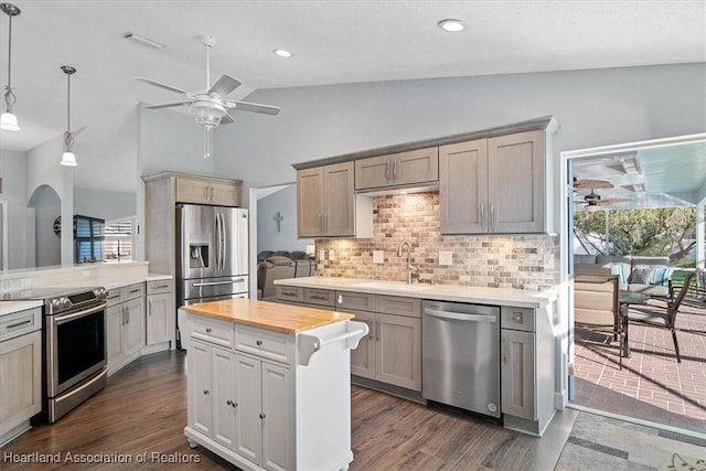 kitchen featuring tasteful backsplash, stainless steel appliances, sink, pendant lighting, and lofted ceiling