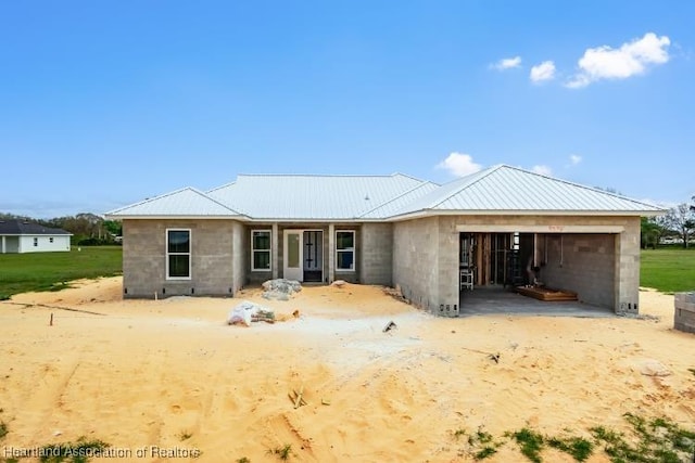 view of front of home with metal roof, concrete block siding, and an attached garage