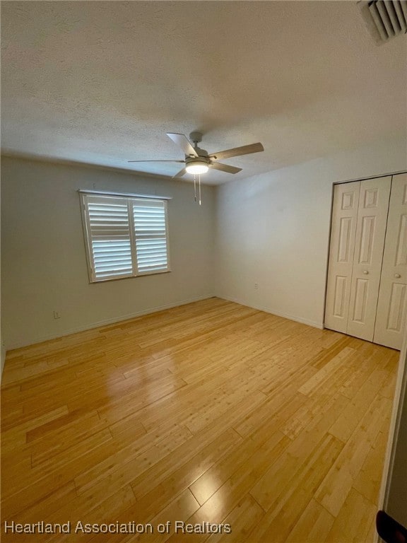 spare room featuring ceiling fan, a textured ceiling, and light wood-type flooring