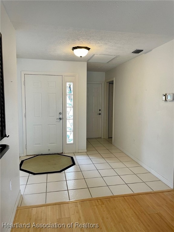 entrance foyer with light tile patterned flooring and a textured ceiling