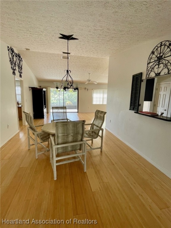 dining space featuring a notable chandelier, a textured ceiling, and light hardwood / wood-style floors