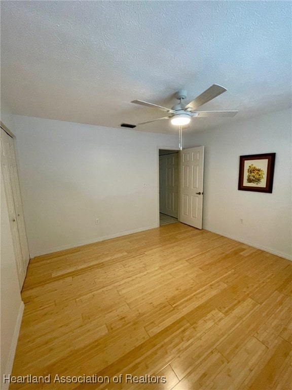 spare room with ceiling fan, a textured ceiling, and light wood-type flooring