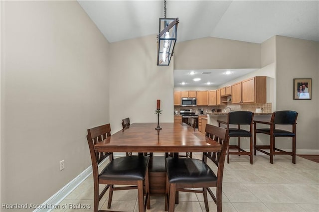 tiled dining space featuring vaulted ceiling