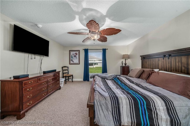 bedroom with ceiling fan, light colored carpet, and a textured ceiling