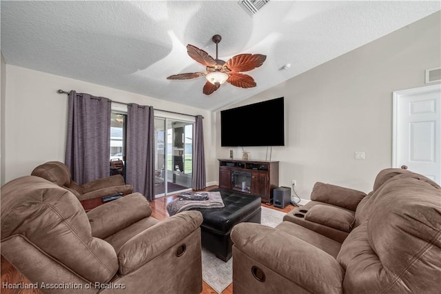 living room with a fireplace, hardwood / wood-style floors, vaulted ceiling, and ceiling fan