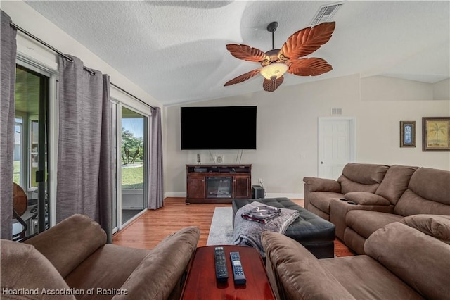 living room with ceiling fan, light hardwood / wood-style floors, lofted ceiling, and a textured ceiling