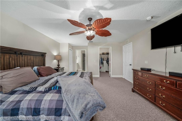 carpeted bedroom with ceiling fan, a spacious closet, a textured ceiling, connected bathroom, and a closet