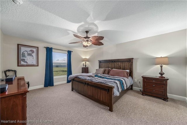 carpeted bedroom featuring ceiling fan and a textured ceiling