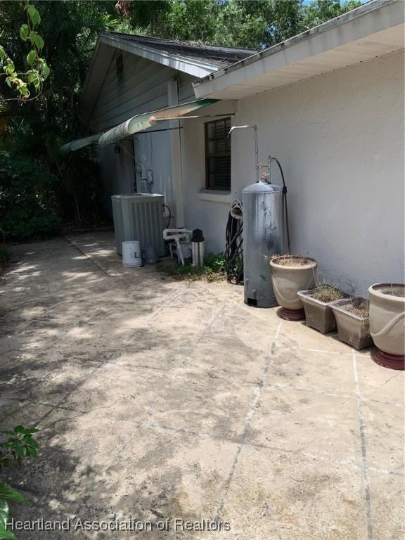 view of patio with central air condition unit and water heater