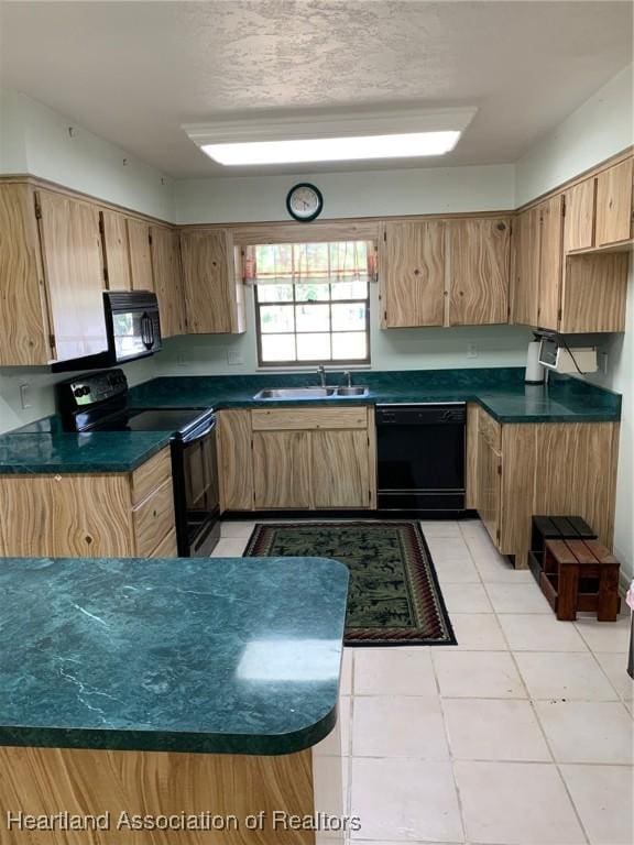 kitchen with a sink, light tile patterned flooring, black appliances, and dark countertops