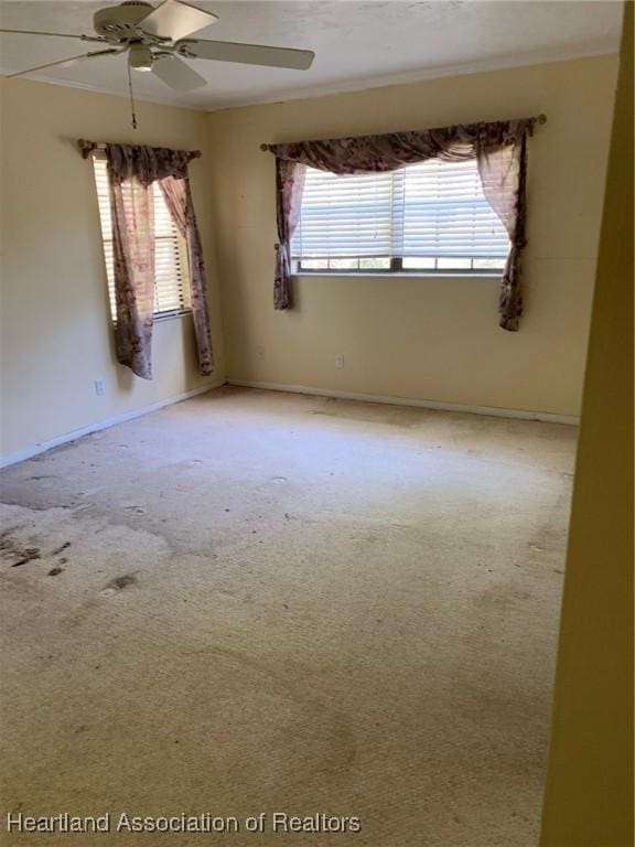 spare room with plenty of natural light, ceiling fan, and light colored carpet