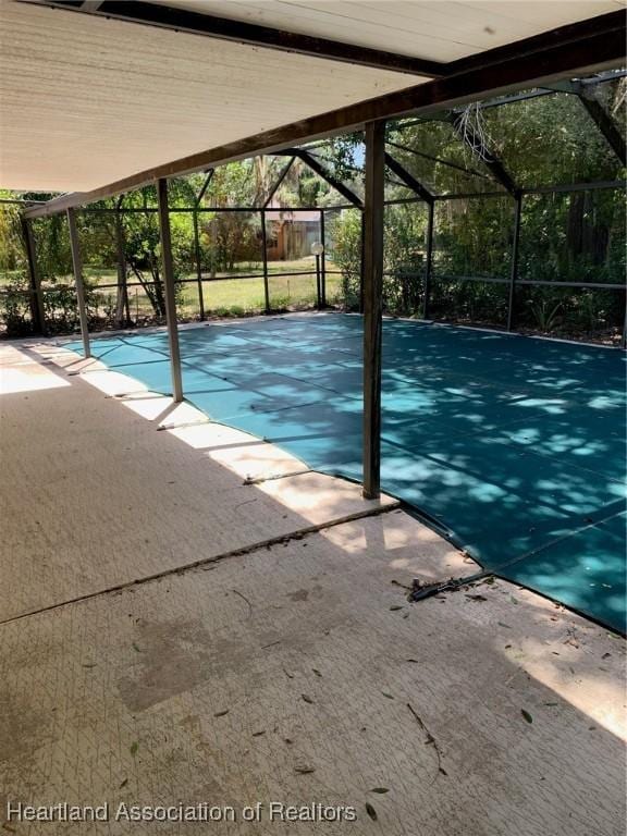 view of swimming pool featuring a patio and glass enclosure