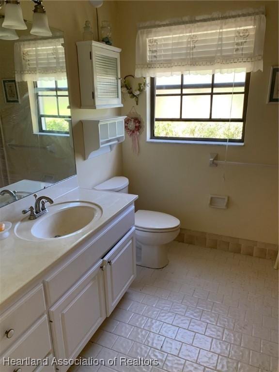 bathroom with plenty of natural light, toilet, and vanity