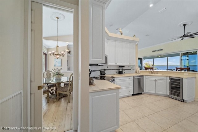 kitchen with lofted ceiling, a water view, white cabinetry, stainless steel appliances, and beverage cooler