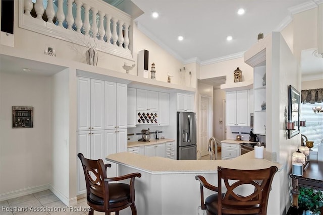 kitchen featuring a breakfast bar area, kitchen peninsula, and white cabinets