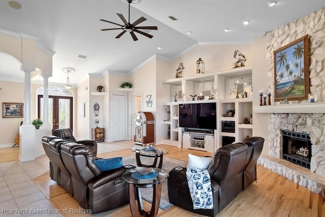 living room with ornamental molding, ceiling fan, light hardwood / wood-style floors, a stone fireplace, and lofted ceiling