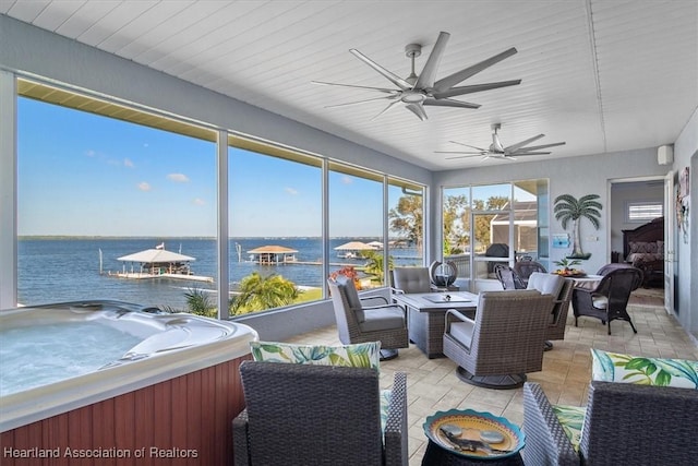 sunroom with ceiling fan, a water view, and a hot tub