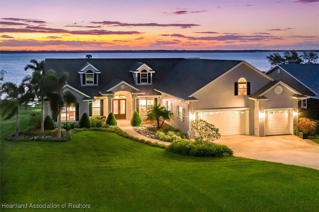 view of front of house featuring a yard, a water view, and a garage