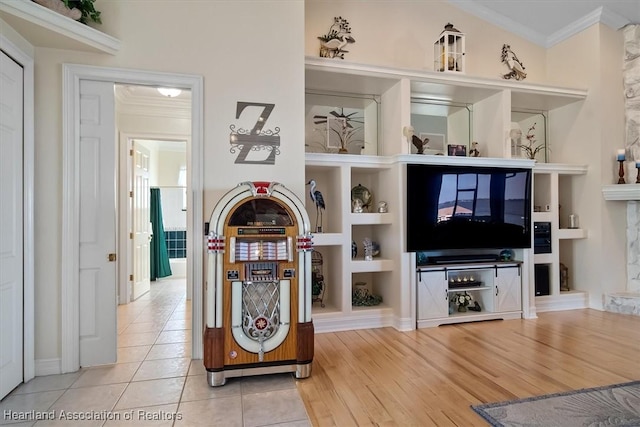 living room featuring built in shelves, tile patterned flooring, and ornamental molding