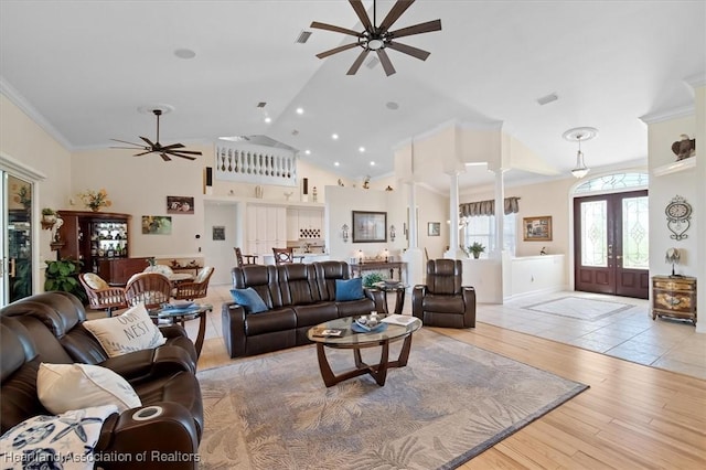 living room featuring french doors, light hardwood / wood-style floors, vaulted ceiling, and ornamental molding