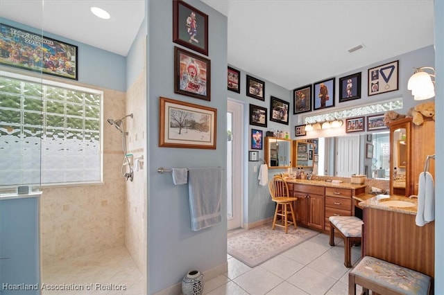 bathroom featuring tile patterned flooring, vanity, and tiled shower