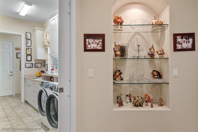 laundry area featuring washer and dryer, cabinets, and sink