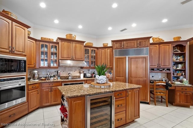 kitchen with wine cooler, backsplash, built in appliances, crown molding, and a kitchen island