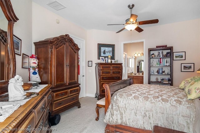 carpeted bedroom with ensuite bathroom and ceiling fan