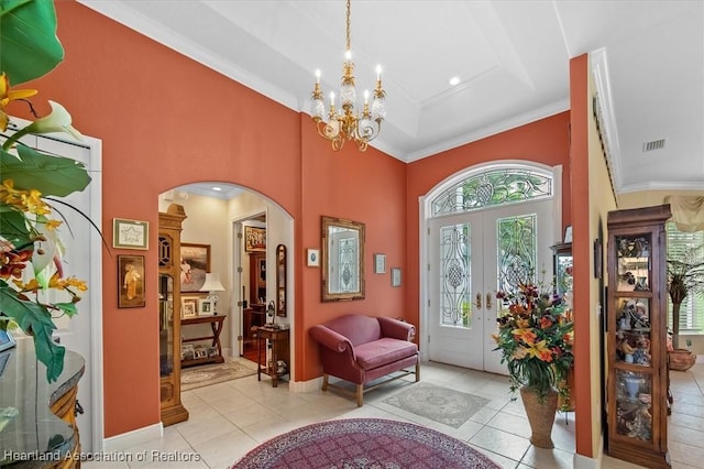 tiled entrance foyer featuring a tray ceiling, crown molding, french doors, and a notable chandelier