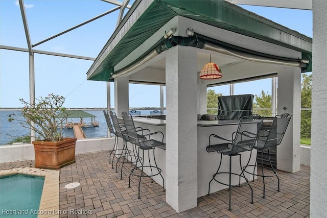 view of patio with glass enclosure, a water view, and exterior bar